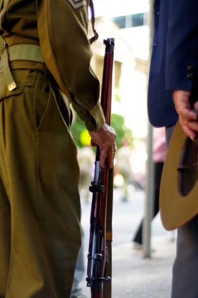 The hand resting on the rifle, the khaki pressed to a perfect crease — historical dress worn with the seriousness it deserves.