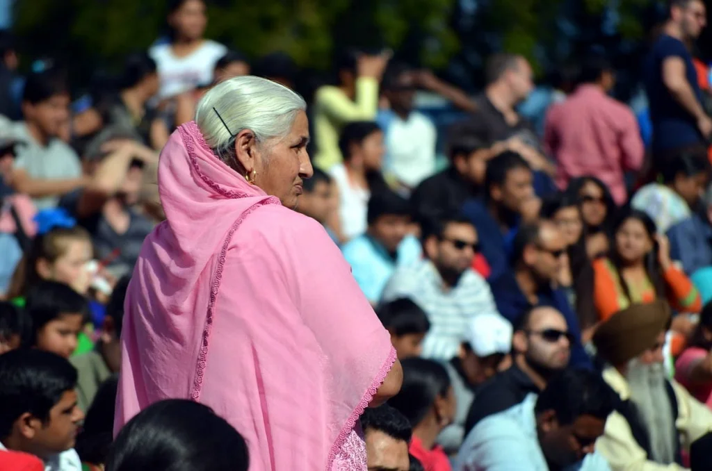 Pink shawl against a crowd of faces, the subject turned away. The back-of-head portrait is underrated.