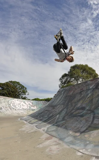 Inverted above the half-pipe, completely upside down, board held in place by muscle memory. The sky is below him and the concrete is above.