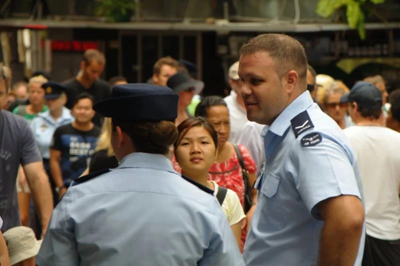 The uniformed crowd is not monolithic. Look for the moment someone in uniform becomes a person — the laugh, the glance sideways, the unguarded expression.