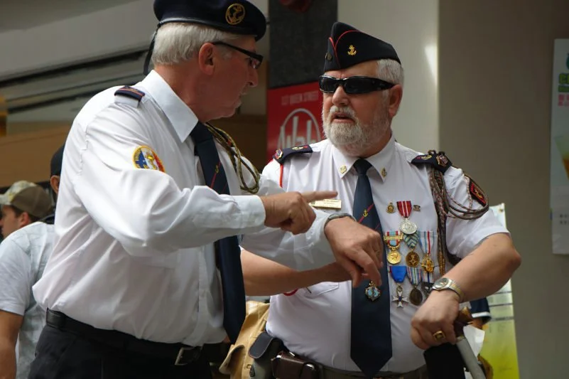 Two veterans talking before the service have a shorthand developed over decades. That conversation will never be fully visible to you. Photograph the surface of it and trust the depth to show through.